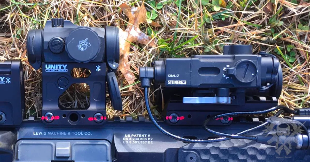 Steiner DBAL-A3 green laser and IR pointer device mounted on AR-15, outdoors on dry grass terrain