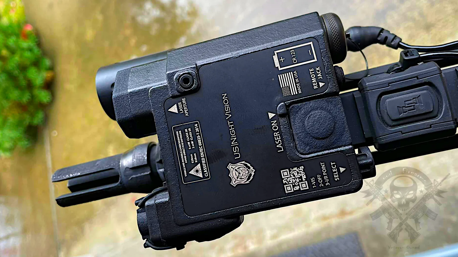 Top-down photo of US Night Vision Designate IR-V showing activation button, remote ports, and labeled laser indicators on aluminum housing