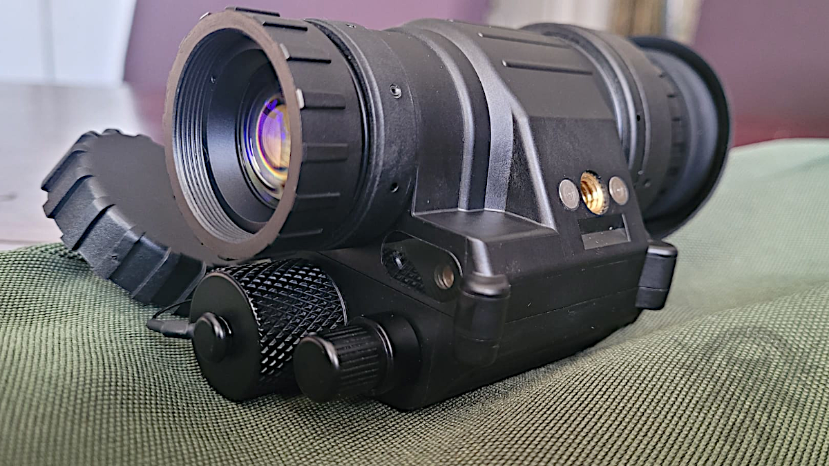 ATN PVS-14 Gen 3 night vision monocular shown in side profile on a soft surface